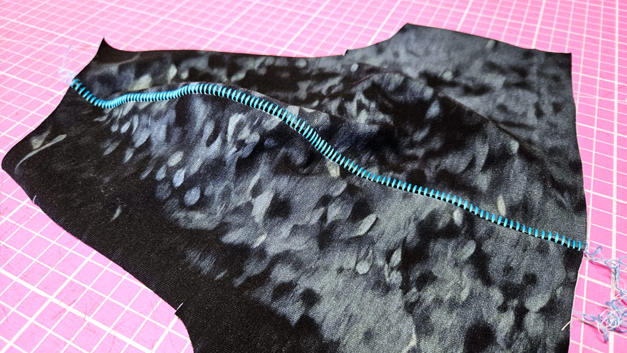 Genähte Flachnaht Overlock am Raglanärmel mit dekorativer hellblauer Leiteroptik.