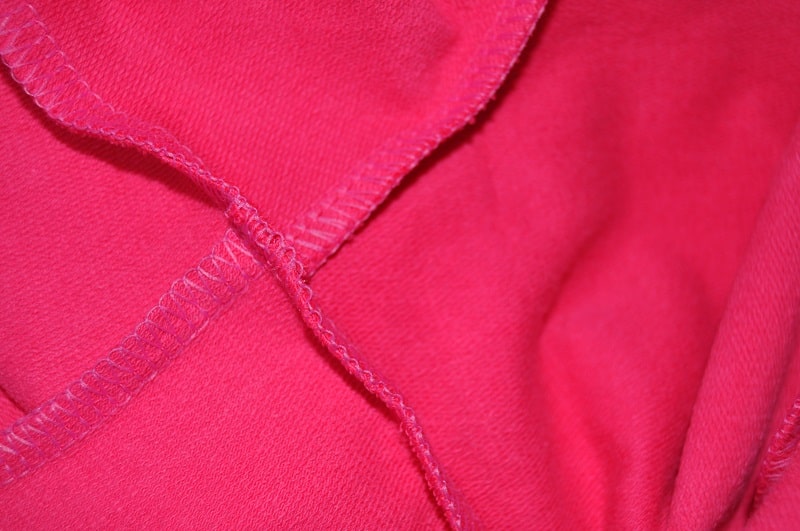 Innenseite einer Nahtkreuzung an einem pinken Shirt mit Overlocknaht
