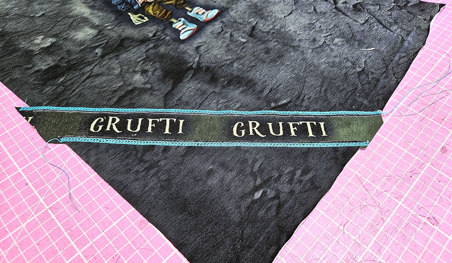 Detailbild einer Negativapplikation am Shirt mit freigelegtem Stoffstreifen und türkisfarbener Covernaht.
