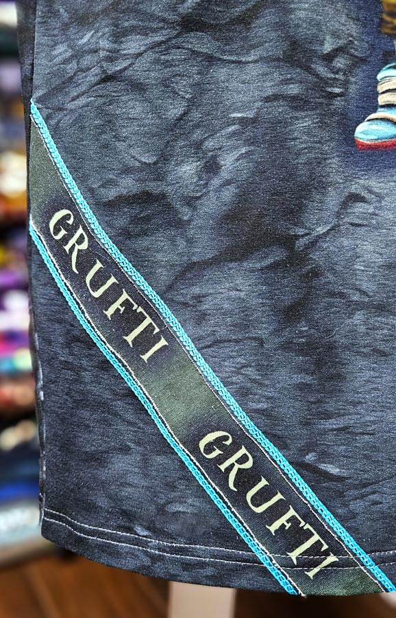 Detail der fertigen Negativapplikation am Shirt mit Schriftstreifen und türkisfarbenen Covernähten.