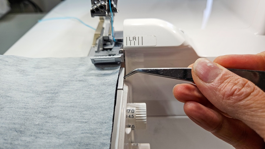 Stoff wird an der Overlock für die Flachnaht geführt, um die richtige Nahtbreite einzuhalten.