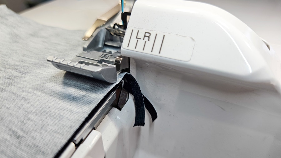 Die Overlock schneidet beim Nähen der Flachnaht einen schmalen Stoffstreifen ab.