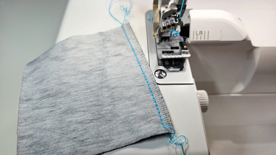 Linke Seite einer genähten Flachnaht Overlock mit sichtbarer Naht auf hellem Stoff.