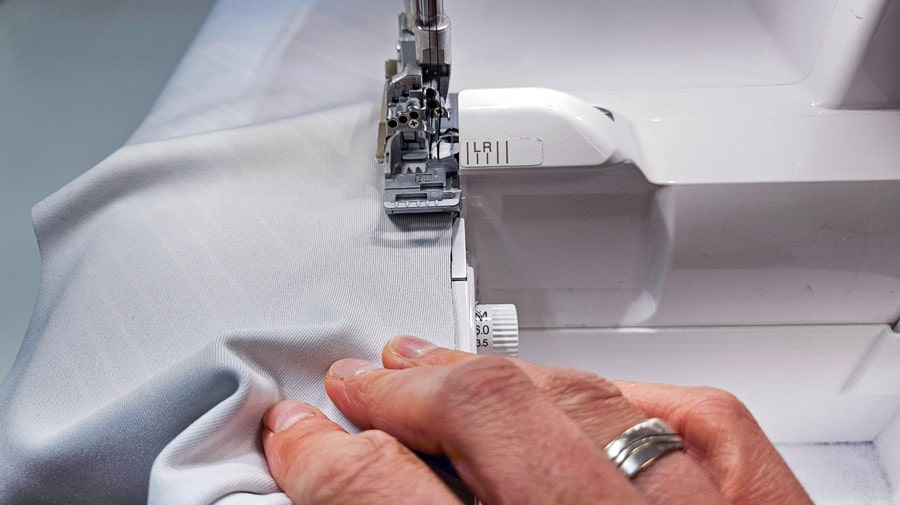Badelycra wird an der Overlock gerade geführt, um die gebogene Rückennaht des Badeanzugs zu nähen.