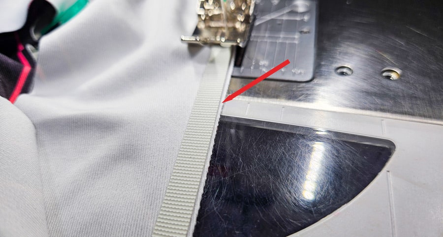 Detailaufnahme eines Badegummis, das knapp neben der Stoffkante angenäht wird.
