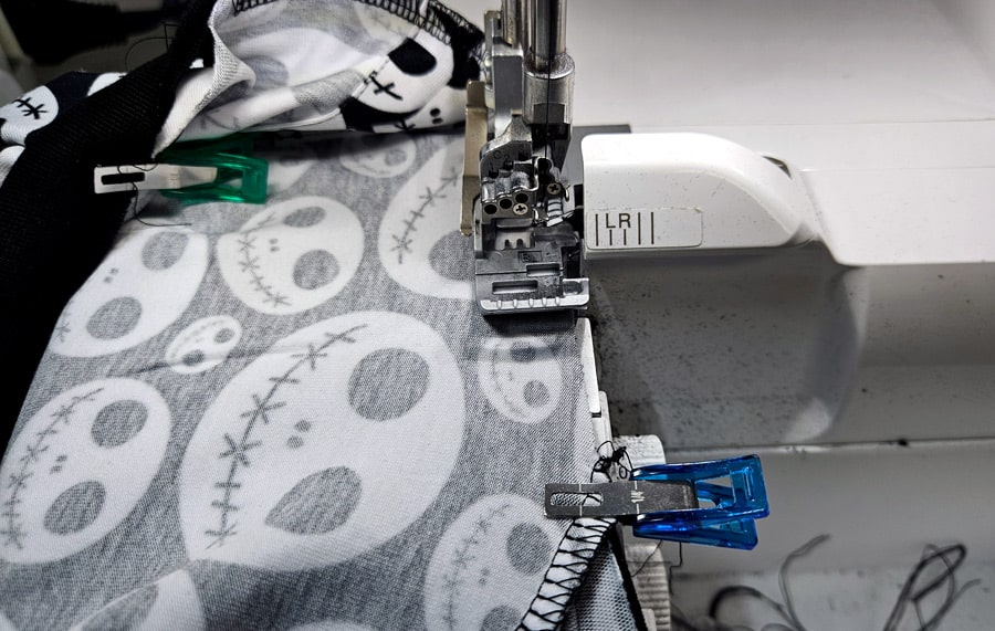 Das Halsbündchen wird mit der Overlock an ein Shirt mit gemustertem Stoff genäht.