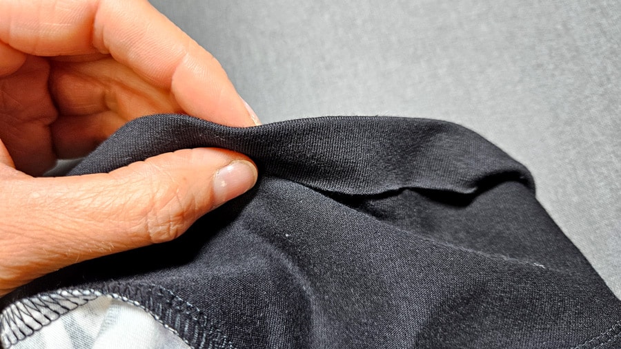 Der Ärmelsaum eines schwarzen Shirts wird für die Wave-Flachnaht umgeschlagen.