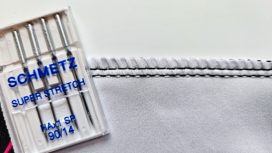 Schmetz Super Stretch Nadeln neben einer Superstretch-Naht auf hellem Badelycra.