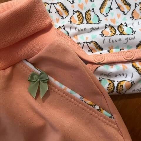 Nahaufnahme einer Babyhose und eines Babybodys mit Igelmuster sowie liebevoll verarbeiteten Details.