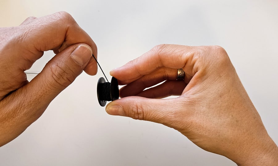Gummifaden wird zum Smoken mit der Nähmaschine von Hand auf eine Unterfadenspule gewickelt.