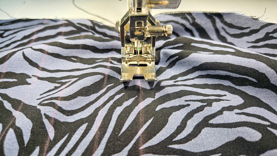 Vorderteil einer Viskosebluse wird entlang der markierten Linien mit der Nähmaschine gesmokt.