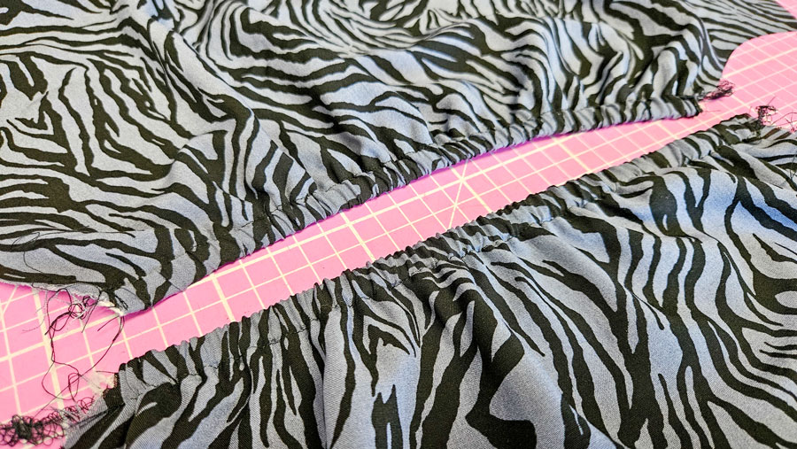 Gummiband wird in den vorbereiteten Tunnel an der oberen Kante der Viskoseärmel eingezogen.