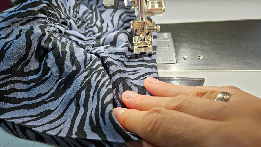 Saum der gemusterten Viskosebluse wird mit der Nähmaschine abgesteppt.