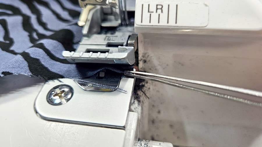 Das Ende der Viskose-Webware wird beim Versäubern mit der Overlock mithilfe einer Pinzette geführt.