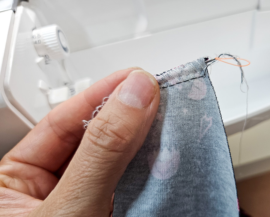 Fadenraupe der Overlocknaht wird mit einer Lassonadel in die Naht gezogen