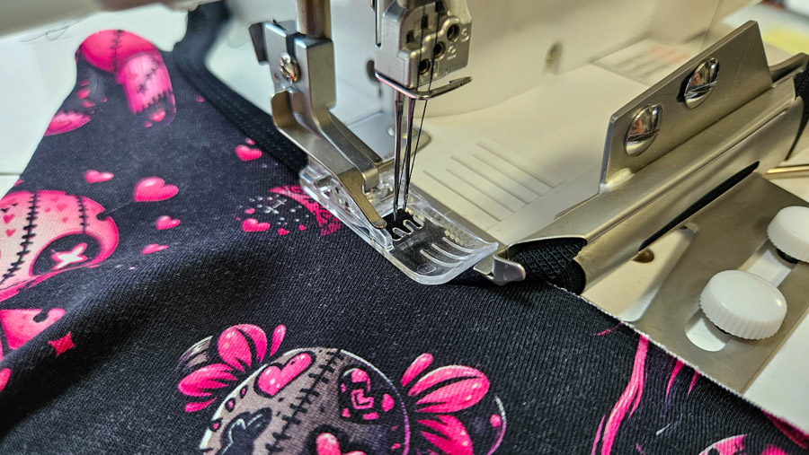 Halsausschnitt eines Jersey-Tops wird mit einem Einfasser an der Coverstitch eingefasst